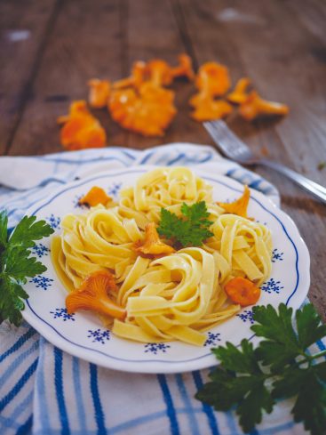 Pâtes fraîches aux girolles et persil sur table bois