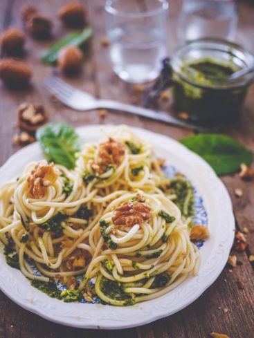 Assiette de spaghettis au pesto et noix sur bois.
