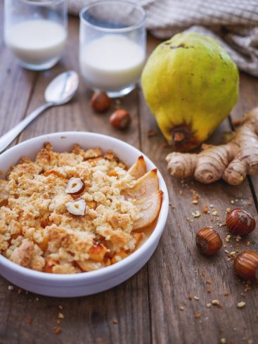 Crumble de coings, lait, gingembre et noisettes sur bois.