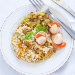 Plat de riz et pétoncles, avec couteau et fourchette.