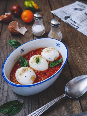 Œufs pochés sauce tomate, basilic, sur table bois