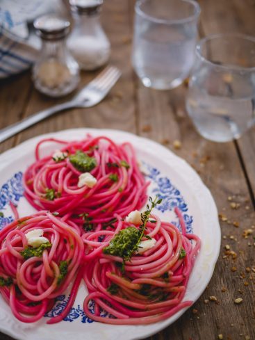 Spaghetti roses au pesto et mozzarella sur assiette.
