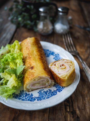 Crêpe roulée jambon fromage avec salade sur assiette