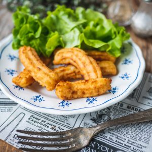 Churros et salade verte sur assiette vintage.