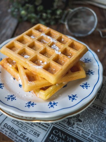 Gaufres fraîches saupoudrées de sucre glace sur assiette.