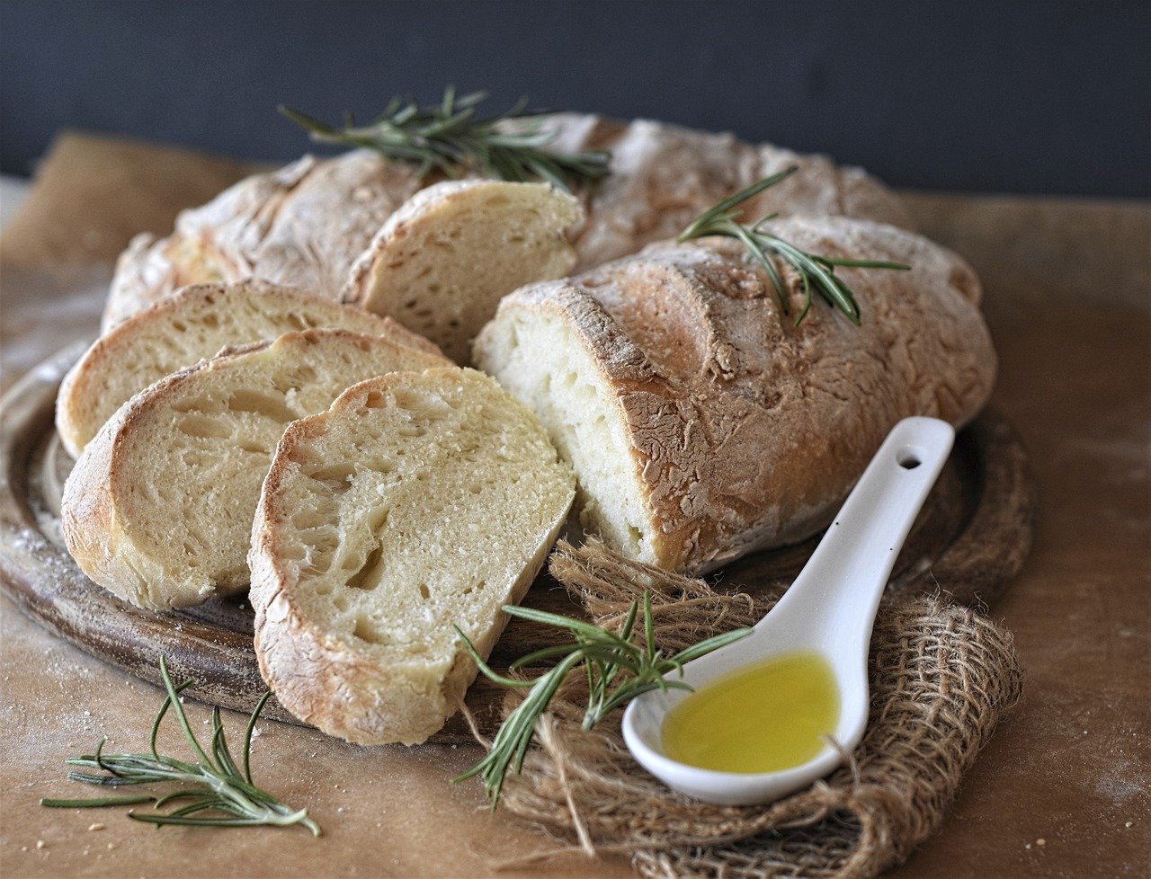 Pain artisanal tranché avec huile d'olive et romarin.
