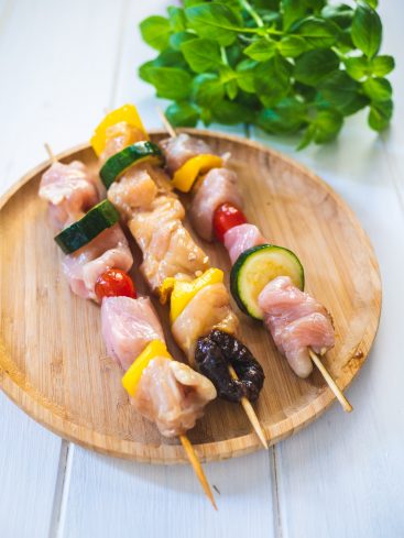 Brochettes de poulet et légumes sur plateau en bois.