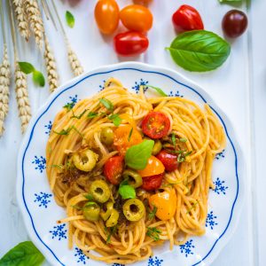 Assiette de spaghetti aux tomates, olives et basilic.