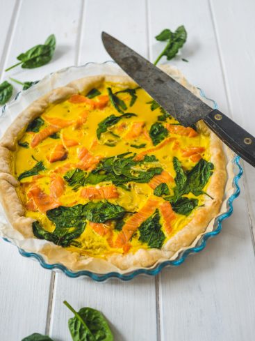 Quiche au saumon et aux épinards, prête à être coupée.