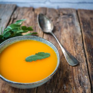 Soupe de potiron avec sauge sur table en bois.