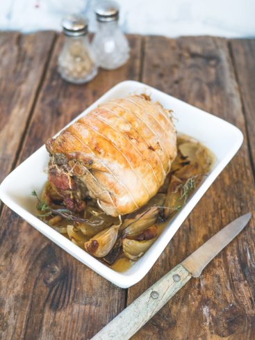 Rôti de porc ficelé avec oignons et ail rôtis.