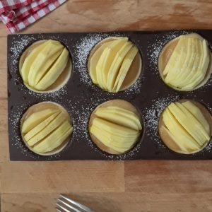 Préparation de tartelettes aux pommes, saupoudrées de sucre glace