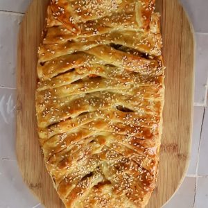 Tresse feuilletée aux graines de sésame sur planche en bois.