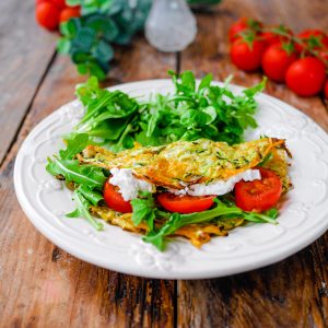 Galette de courgette, tomates et roquette sur assiette.