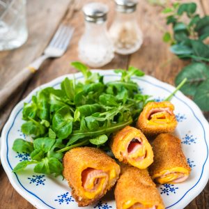 Cordons bleus frits avec salade verte sur assiette.
