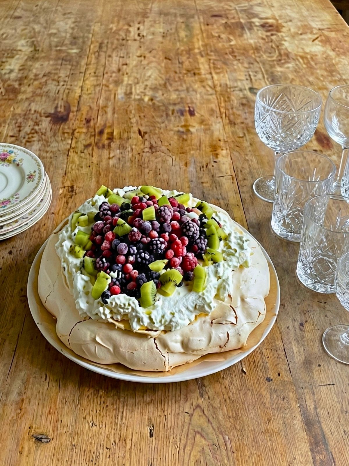 Pavlova aux fruits rouges et kiwis sur table en bois