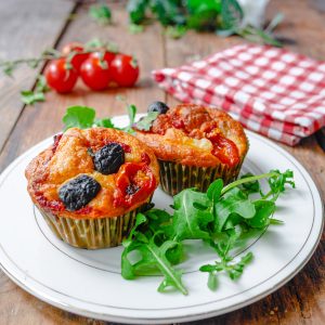 Deux muffins salés aux tomates et olives sur assiette.