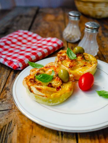 Mini quiches garnies sur assiette blanche, nappe vichy rouge.