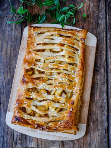 Tarte aux pommes feuilletée sur planche en bois.