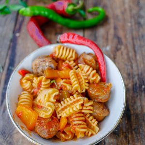 Pâtes, saucisses et poivrons avec piments sur bois