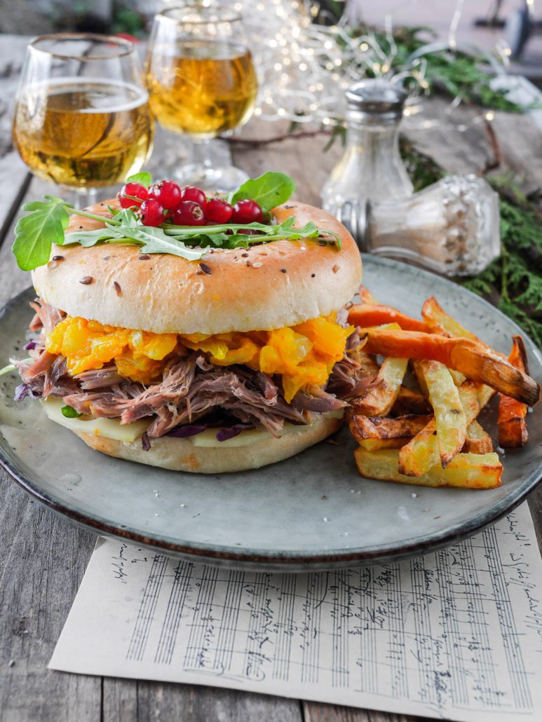 Bagel garni de lapin de garenne effiloché, servi dans une assiette avec des frites