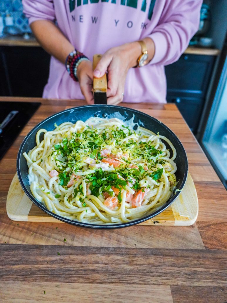 une poêle avec des spaghettis au saumon, à la crème, zestes de citron et persil haché