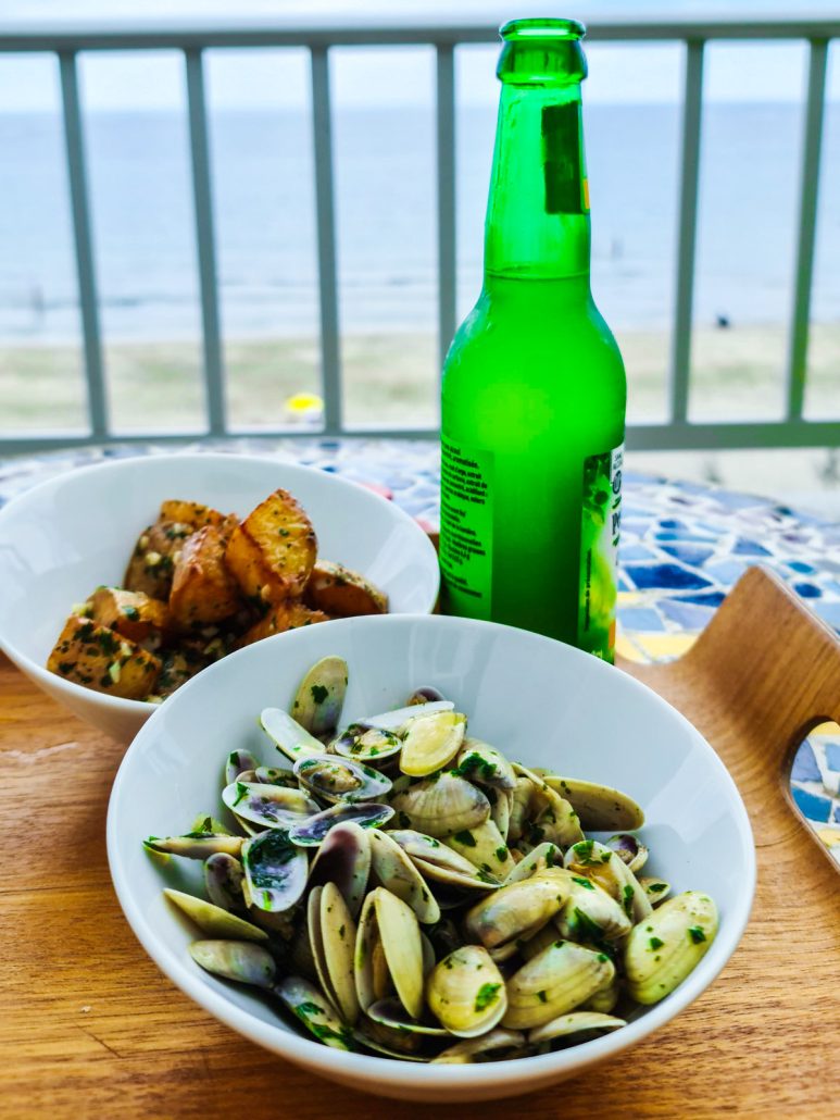 Bol de tellines à la persillade pour l'apéro posé sur une table face à la mer