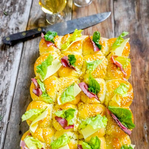 Une brioche salée garnie de charcuterie et de fromage et de salade verte, servie avec des verres de apéro