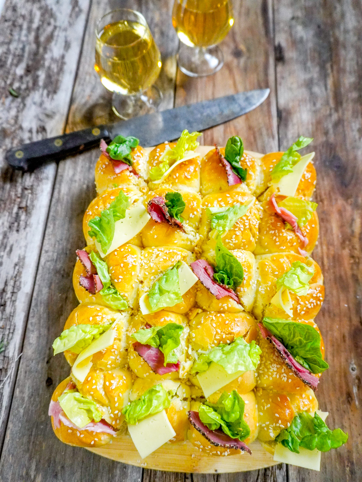 Une brioche salée garnie de charcuterie et de fromage et de salade verte, servie avec des verres de apéro