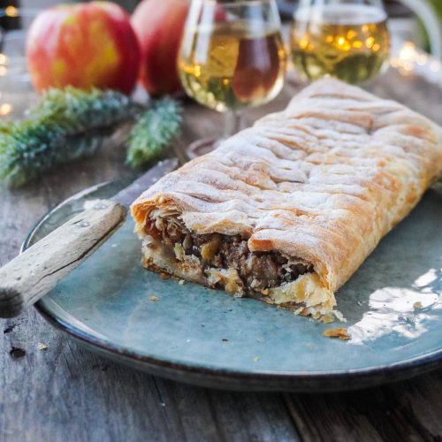 Strudel aux pommes tranché, posé dans une assiette sur une table festive