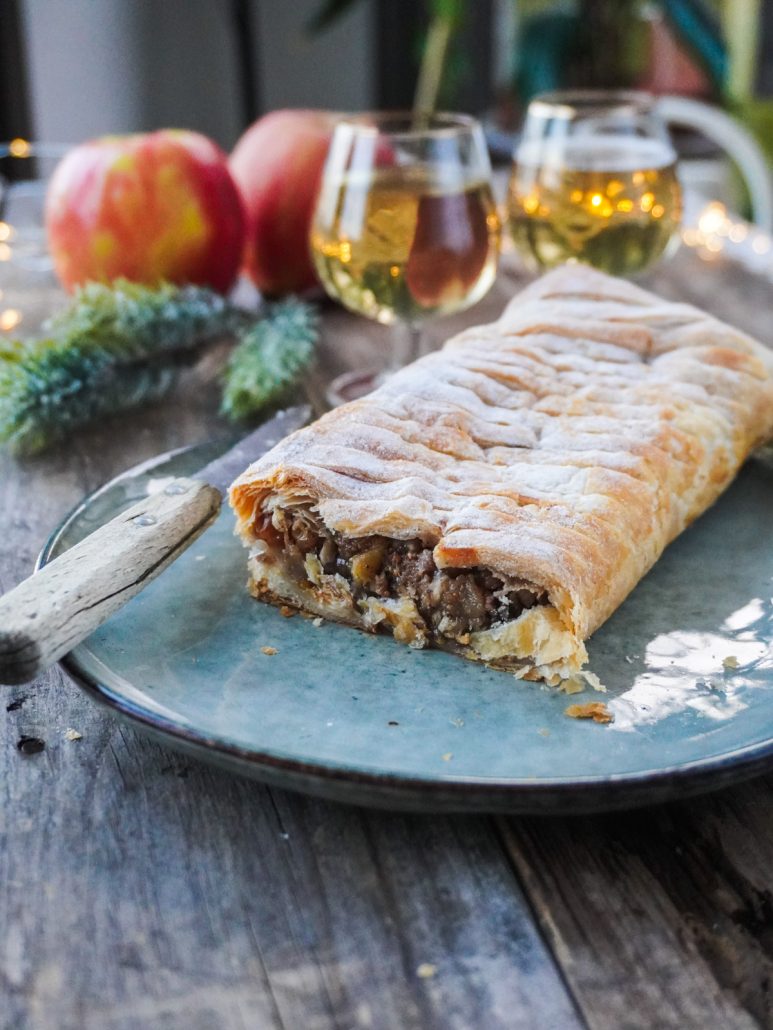 Strudel aux pommes tranché, posé dans une assiette sur une table festive