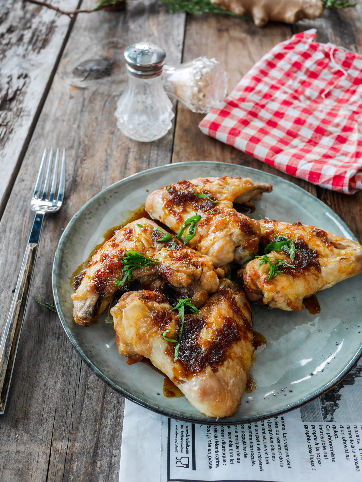 Poulet laqué sur assiette, fourchette et accessoires culinaires.