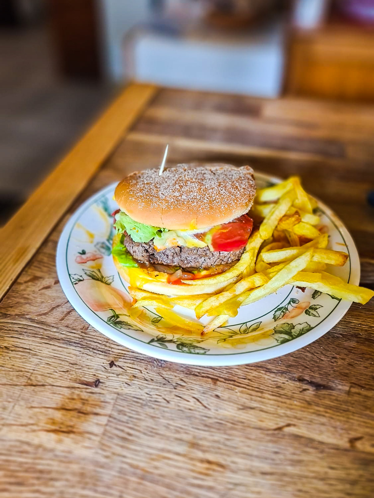 Burger appétissant avec frites sur une assiette fleurie.