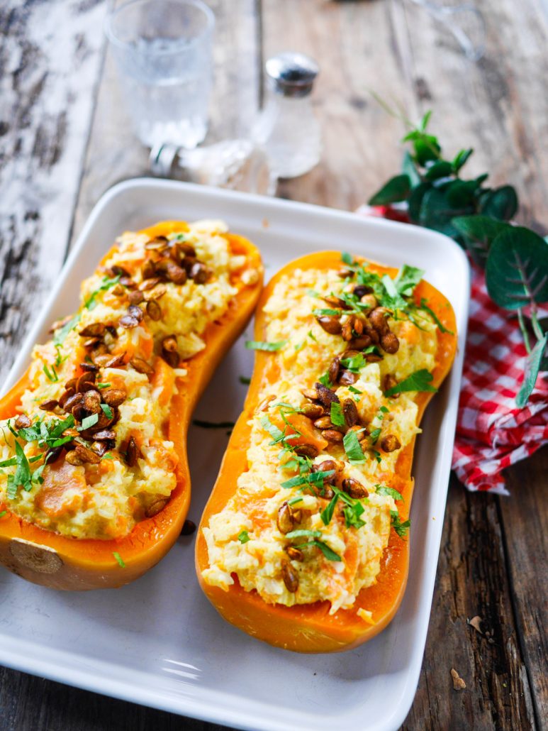 Courge butternut au riz, garnie de persil et de graines de butternut grillées, posée sur une plat à gratin
