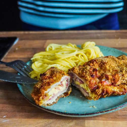 Cordon bleu fait maison, fromage et jambon, posé dans une assiette et coupé en deux.