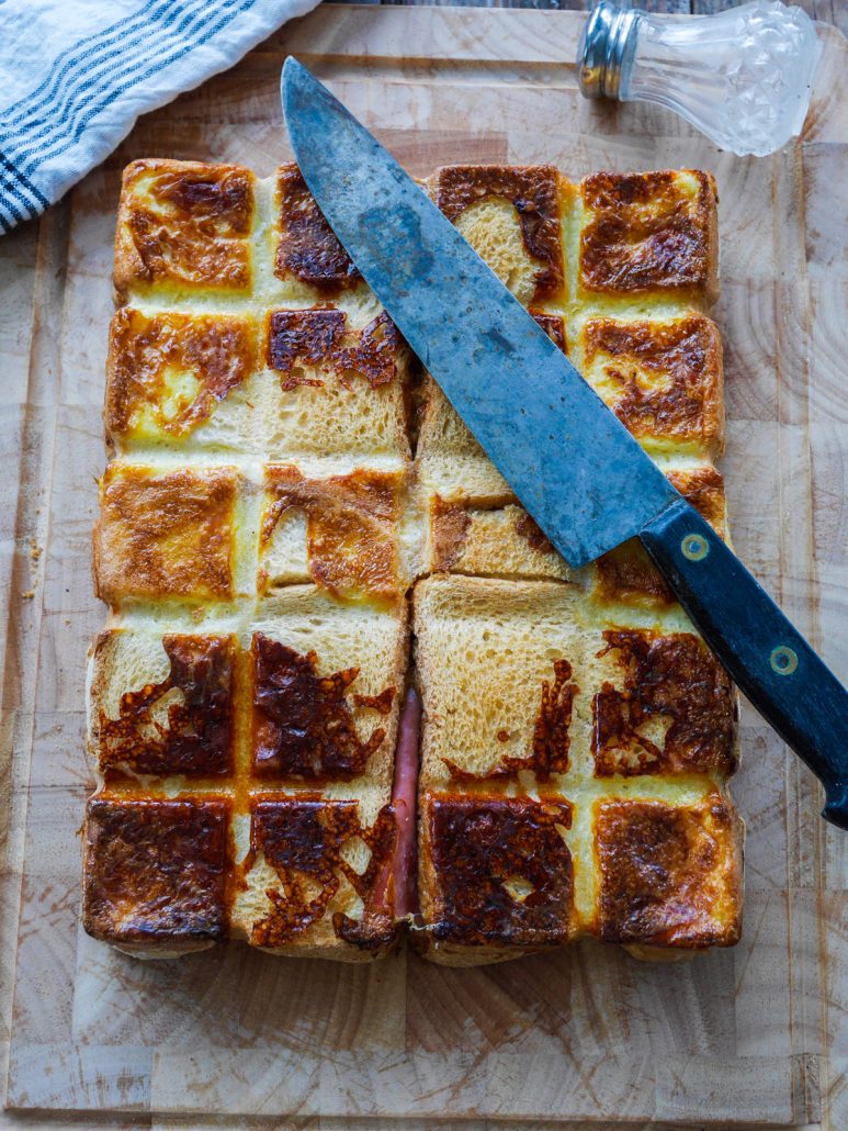 Croque monsieur géant cubicube sur une planche à découper avec un couteau de cuisine