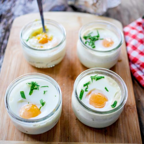 Oeufs cocotte maison en bocaux sur planche en bois.