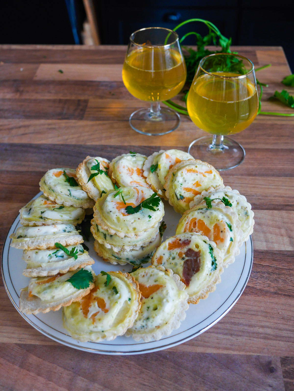 Mini quiches apéritives et boissons dorées sur table en bois