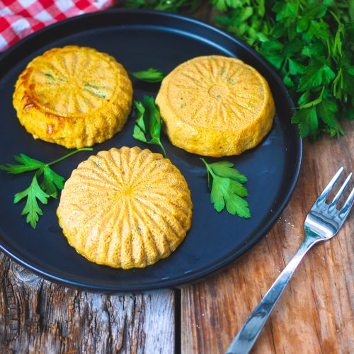 Flans aux légumes sur assiette noire, persil, fourchette.