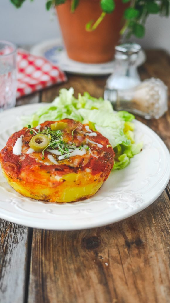 une assiette avec salade verte et une galette de pomme de terre façon pizza