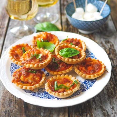 Mini-pizzas, vin blanc et mozzarella sur table boisée