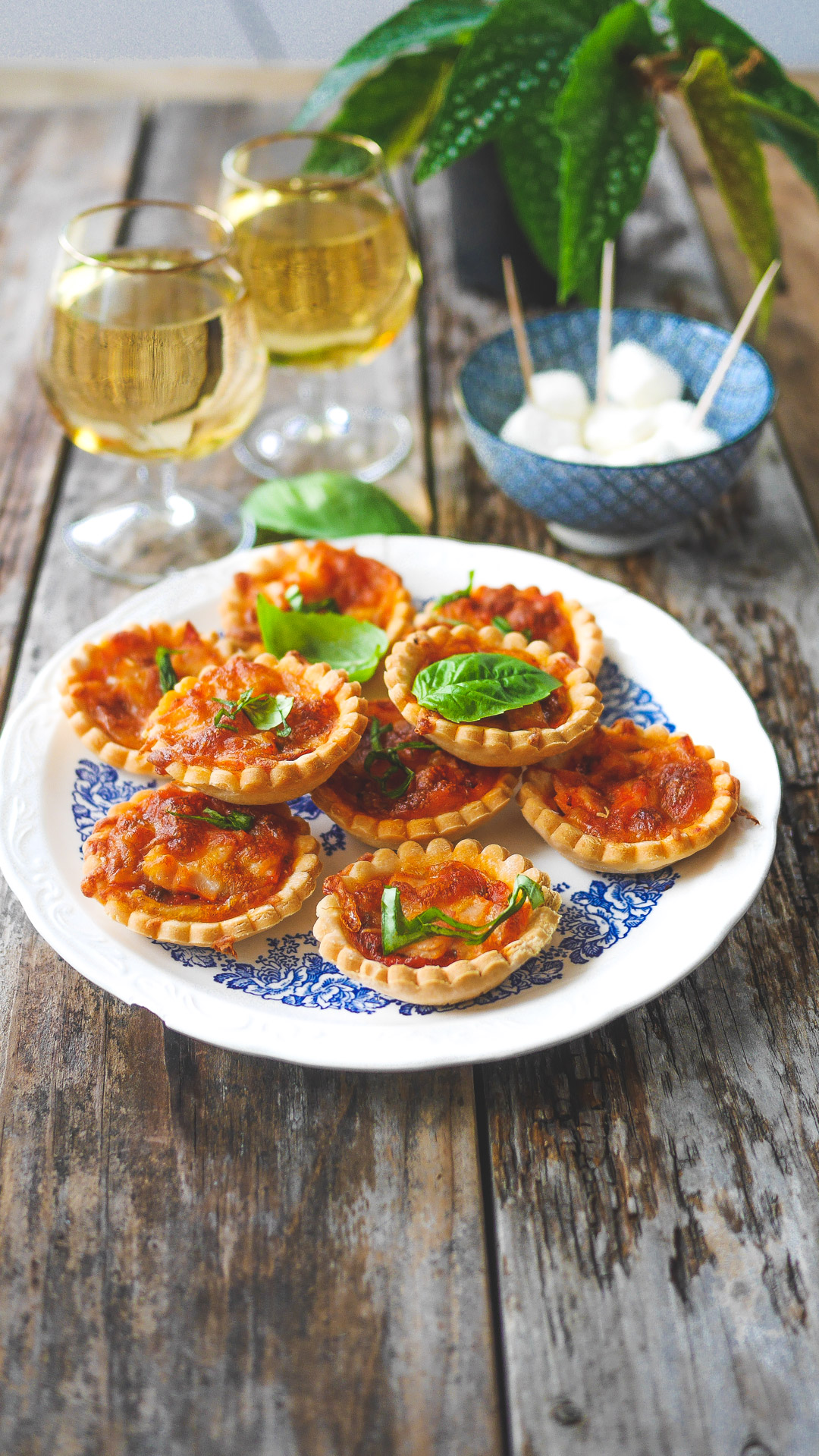 Mini-pizzas, vin blanc et mozzarella sur table boisée