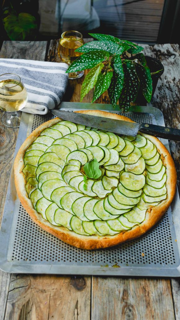 une tarte fine courgette basilic, posée sur la grille de cuisson, prête à découper