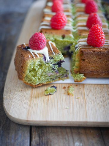 Gâteau matcha, framboises et glaçage sur planche à découper.