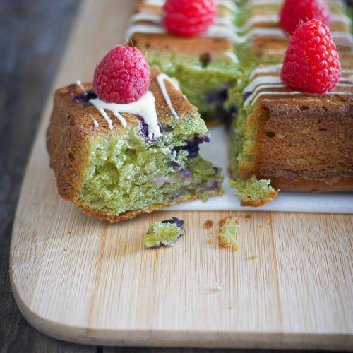 Gâteau matcha, framboises et glaçage sur planche à découper.