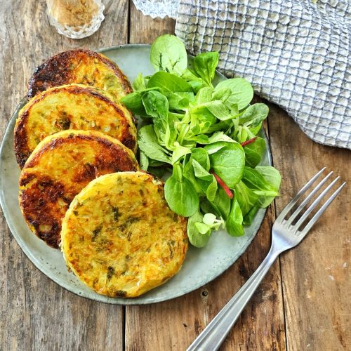 Galettes de légumes et salade verte sur table bois