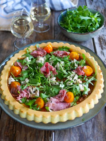 Tarte salée avec roquette, tomates, viande et fromage.