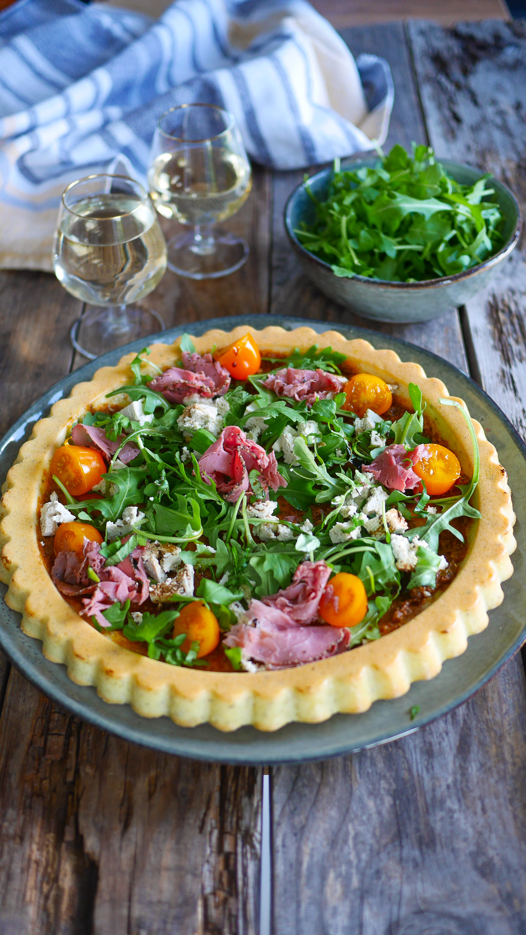 Tarte salée avec roquette, tomates, viande et fromage.