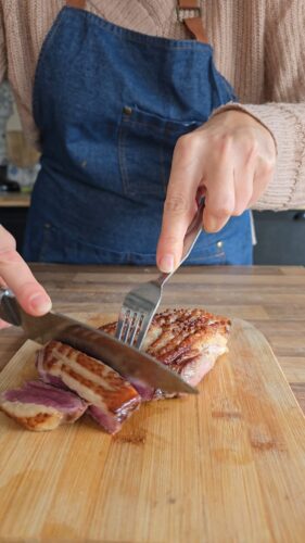 Magret de canard coupé sur planche à découper.