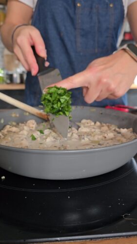 Ajout de persil frais à un plat en sauce.